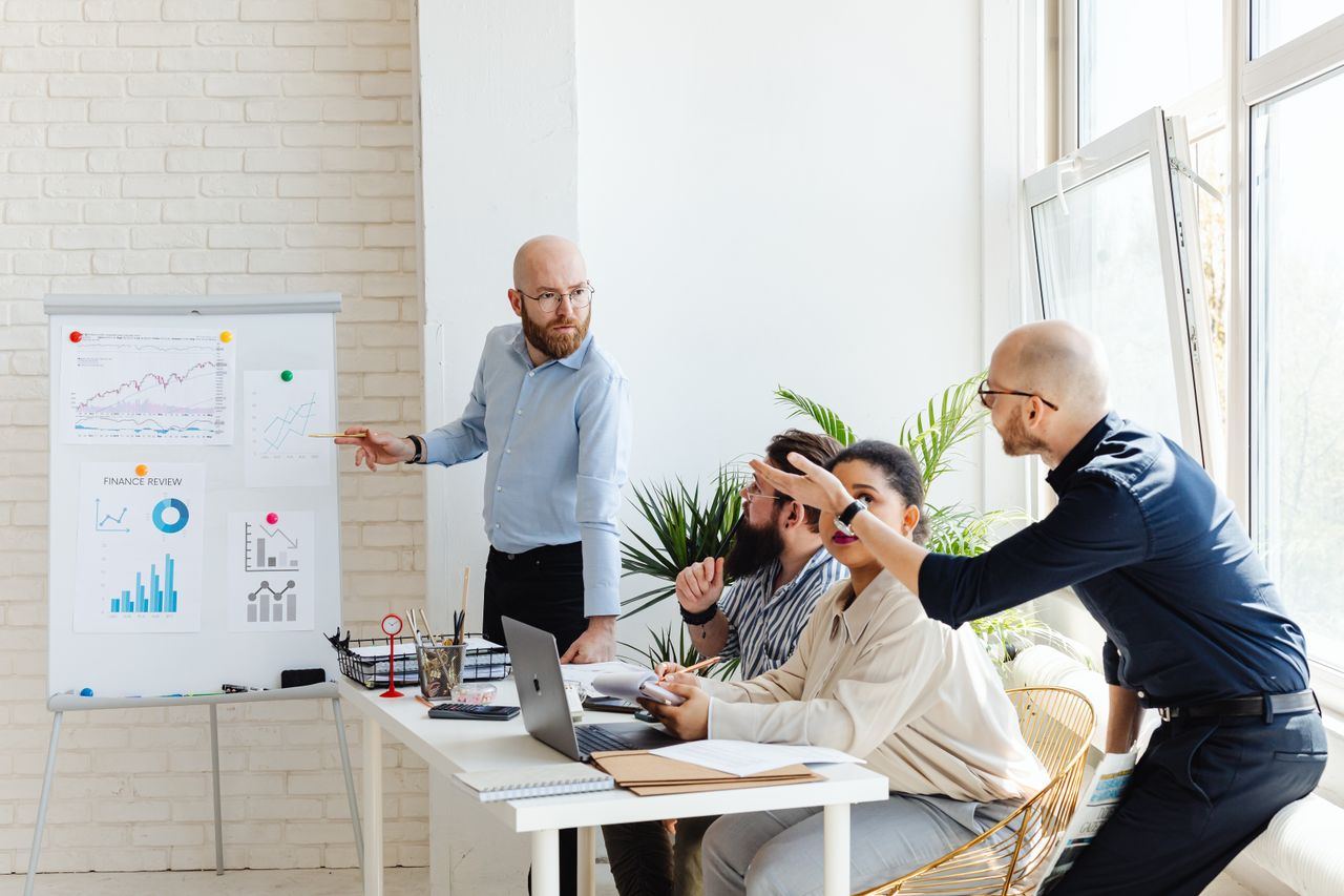 about-bg A group of professionals engaged in a business meeting, discussing financial graphs on a whiteboard.